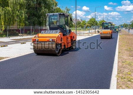 Vibratory asphalt roller compactor on site, compacting new asphalt pavement in urban modern city  Royalty-Free Stock Photo #1452305642