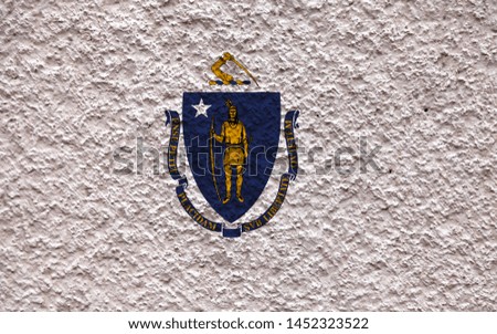 The national flag of the US state Massachusetts in against a gray wall with stony surface on the day of independence in blue white and yellow. Political and religious disputes, customs and delivery