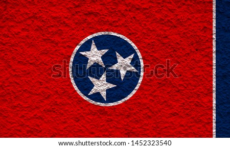 The national flag of the US state Tennessee in against a gray wall with stony surface on the day of independence in colors of blue red. Political and religious disputes, customs and delivery.