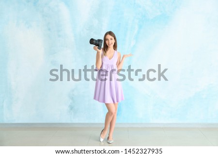 Young female photographer against color wall