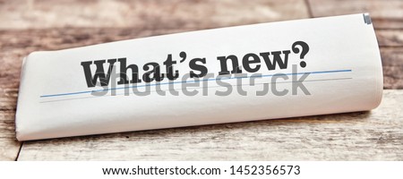 What's new as the title of a folded newspaper on a wooden table Royalty-Free Stock Photo #1452356573