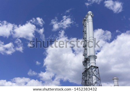 Observation tower on the blue background. Blue sky with clouds. Manufacture background. White tower on a blue background. Commercial texture. Factory view. 