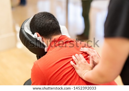 Man seated in a massage chair for back massage. Royalty-Free Stock Photo #1452392033