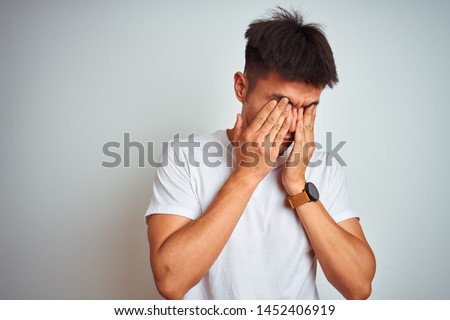 Young asian chinese man wearing t-shirt standing over isolated white background rubbing eyes for fatigue and headache, sleepy and tired expression. Vision problem