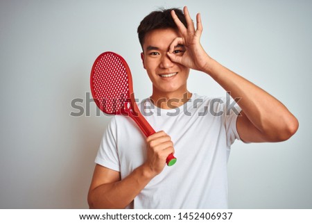 Asian chinese sportsman holding tennis racket standing over isolated white background with happy face smiling doing ok sign with hand on eye looking through fingers