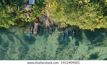 Aerial view of natural clear blue sea with sea floating bridge and boat.  with fishing boats and long tail taxi boats parking along the sand beach, Biak Papua Indonesia