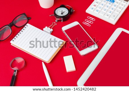 Red office desk table with blank notebook, keyboard and supplies. Top view with copy space. Flat lay.