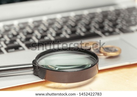 Laptop computer keyboard with magnifying glass, concept of search