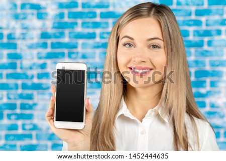beautiful woman holding and showing white mobile phone with blank black screen