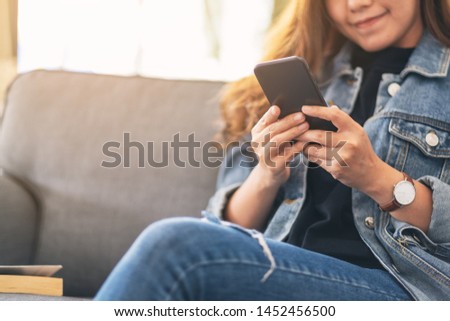 Closeup image of a beautiful asian woman holding , using and looking at smart phone