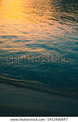 Waters Edge With Colorful Sunrise Reflected on Ripples on the Sea Background