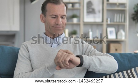 Middle Aged Man Relaxing on Couch and Using Smartwatch Applications