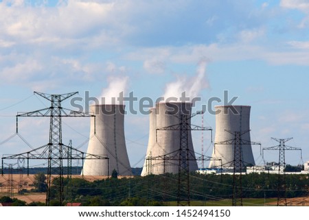 View of smoking chimneys of nuclear power plant, power lines and forest, under blue sky with white clouds Royalty-Free Stock Photo #1452494150