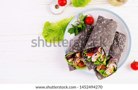 Tortilla with added ink cuttlefish wraps with chicken and vegetables on white background. Chicken burrito, mexican food. Top view