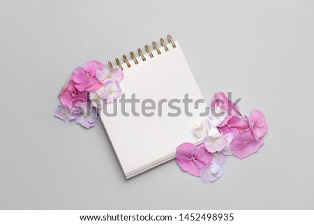 Beautiful hydrangea flowers and notebook on light background