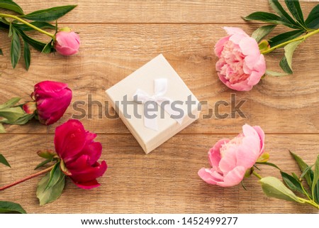 White gift box on wooden boards decorated with flowers of peony. Top view.