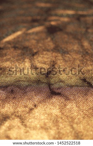 Golden glittering cloth texture as background. Shallow DOF with defocused and blurred edges.