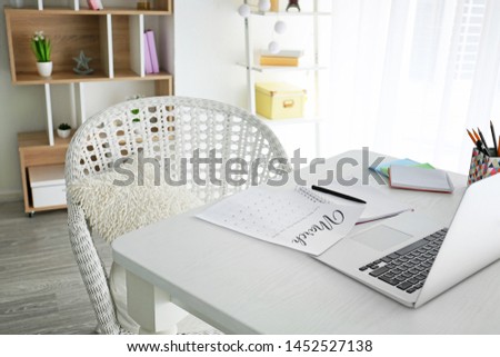 Page of calendar with laptop and stationery on table