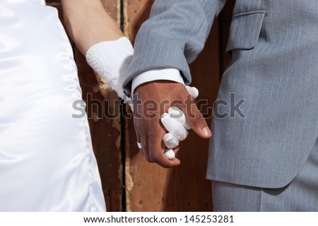Closeup of holding hands of stylish wedding couple. Mixed race. Royalty-Free Stock Photo #145253281