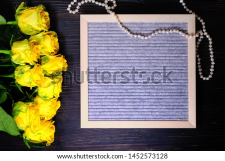 Bouquet of roses on a dark wooden background, copy space for Valentine's day card. Pearl beads next to a bouquet of flowers. Beautiful yellow flowers and chalkboard label.