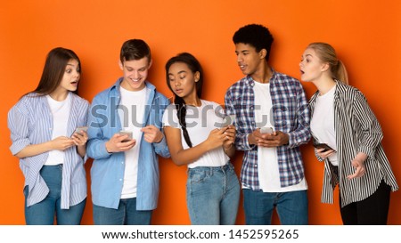 Teens spying friend phone, texting or surfing social networks over orange background