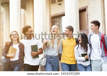 Happy students walking together in campus, having break in university Royalty-Free Stock Photo #1452595289