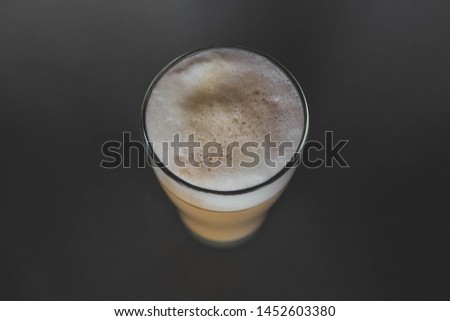 A large transparent glass filled with Latte cooked in a third wave coffee shop is photographed on a gray, isolated background, photo for the menu