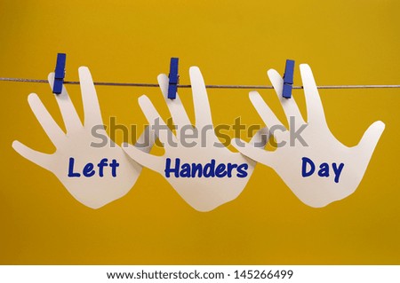 Left Handers Day message greeting across left hand silhouette cards hanging from pegs on a line against a yellow background, for International Left-handers Day on August 13. Royalty-Free Stock Photo #145266499