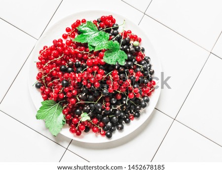 Fresh ripe red and black currant on light background, top view