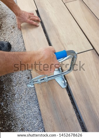paving a patio - fitting the stone tile with a slab heaver, detail shot