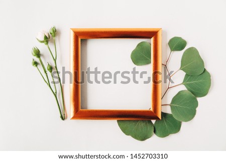 Creative and stylish mockup with green leaves and golden frame.Minimalist flat lay,white simple background.Floral frame
