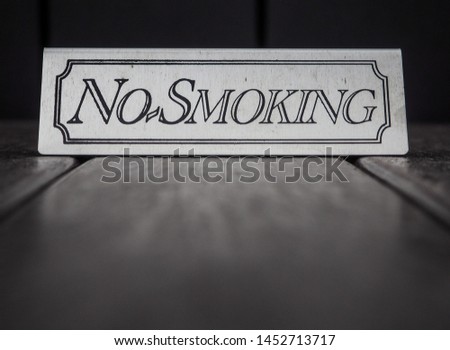 Engraved metal no smoking sign on hotel's outdoor bistro table.