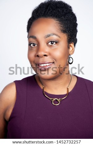 corporate African American business woman with an Afro is wearing jewelry and business attire for professional head shots. shot on white and grey isolated backdrop