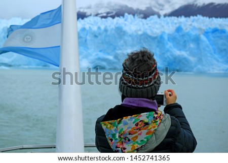 Female Tourist taking Photos of the Awesome Glacier Wall of Perito Moreno Glacier from the Cruise Ship on Lake Argentino, Patagonia, Argentina, South America