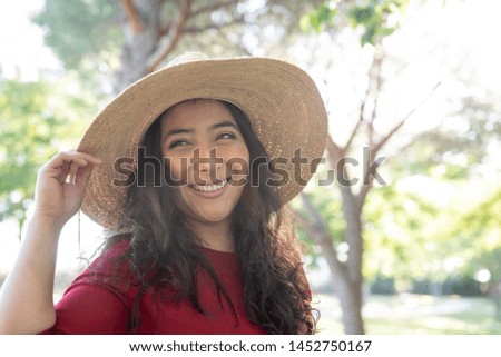 Pretty Hispanic woman in the park with her hat, showing her beautiful long hair