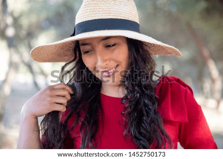 Pretty Hispanic woman in the park with her hat, showing her beautiful long hair