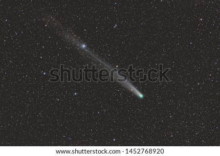 Real photo comet C / 2013 R1 Lovejoy. The date of shooting is December 27, 2013. A comet with a long tail flies through space. Natural background.