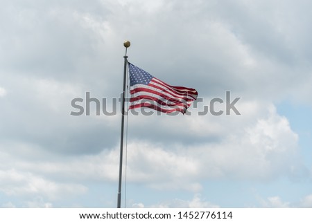 Lone stars and stripes on the flag of America waving in against a cloudy sky in summer.