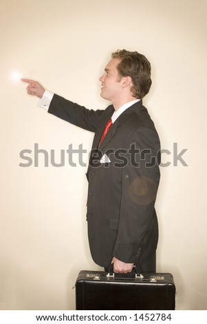 Business man in black suit, red tie, and white shirt holding briefcase, pointing his right finger up in the air