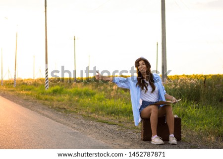 tourist sits on a suitcase with a map sunset road trip woman in shirt