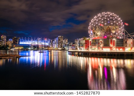 View of illuminated Vancouver skyline at night and reflection in water. British Columbia, Canada.