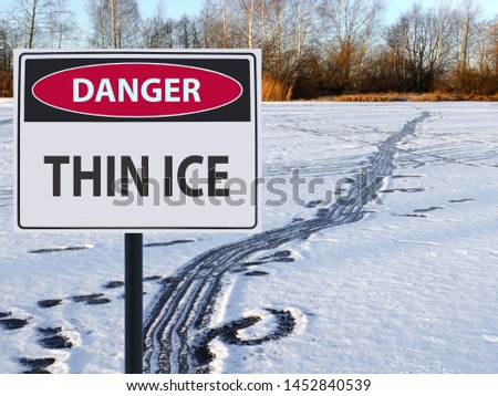 sign thin ice and footprints and road on snow and ice
