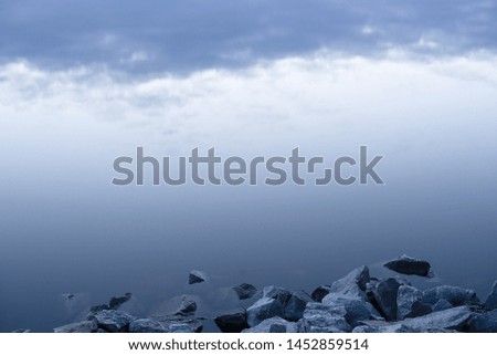 Gray evening sunset above the lake or river. Blue clouds on horizon. Abstract picture.