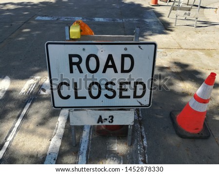White Road Closed Construction Sign with Orange Traffic Cones