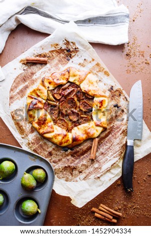 Figs galette made with pastry crust and fresh fig on a cooking paper over a wooden board, top view.