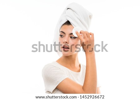 Teenager girl over isolated white backgroundremoving makeup from her face with cotton pad