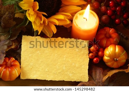 Arrangement of sunflower, candle and autumn decorations on wooden background with paper copy space.