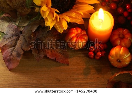 Arrangement of sunflower, candle and autumn decorations on wooden background with copy space.