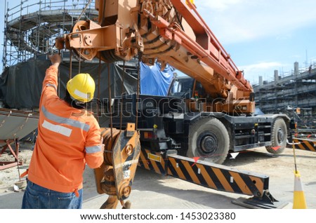 Crane operator conducting safety inspecting on the wire sling which attached with crane lifting hook prior completed his daily work construction site Royalty-Free Stock Photo #1453023380