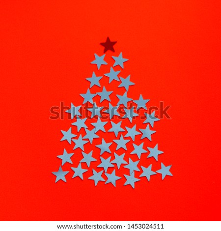 Stars shine in the form Christmas tree silhouette on red background. Minimal composition with copy space, flat lay, top view. Creative concept